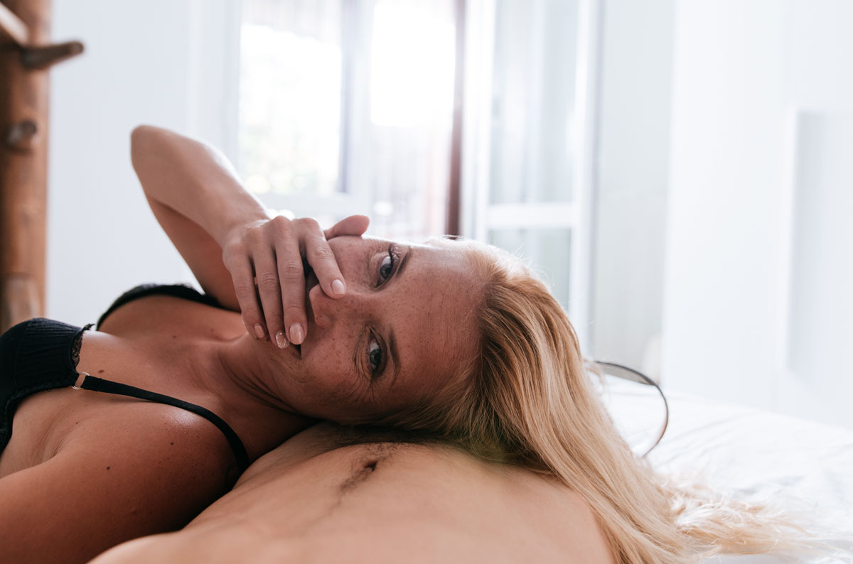 Une femme cougar satisfaite de son plan cul sourit couchée sur son jeune sexfriend.